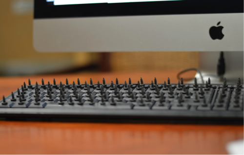 Computer keyboard with spikes inserted into each of its keys.